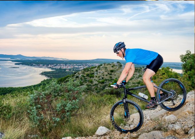 Mężczyzna zjeżdża z góry na lekkim rowerze trekkingowym